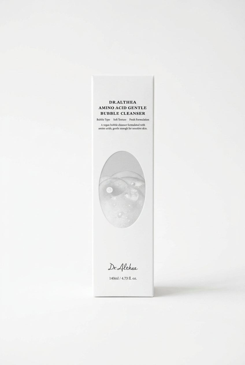 A long, slim white product box for Dr. Althea Amino Acid Gentle Cleanser, featuring a circular abstract graphic in the center and black text, placed on a dark wooden surface.