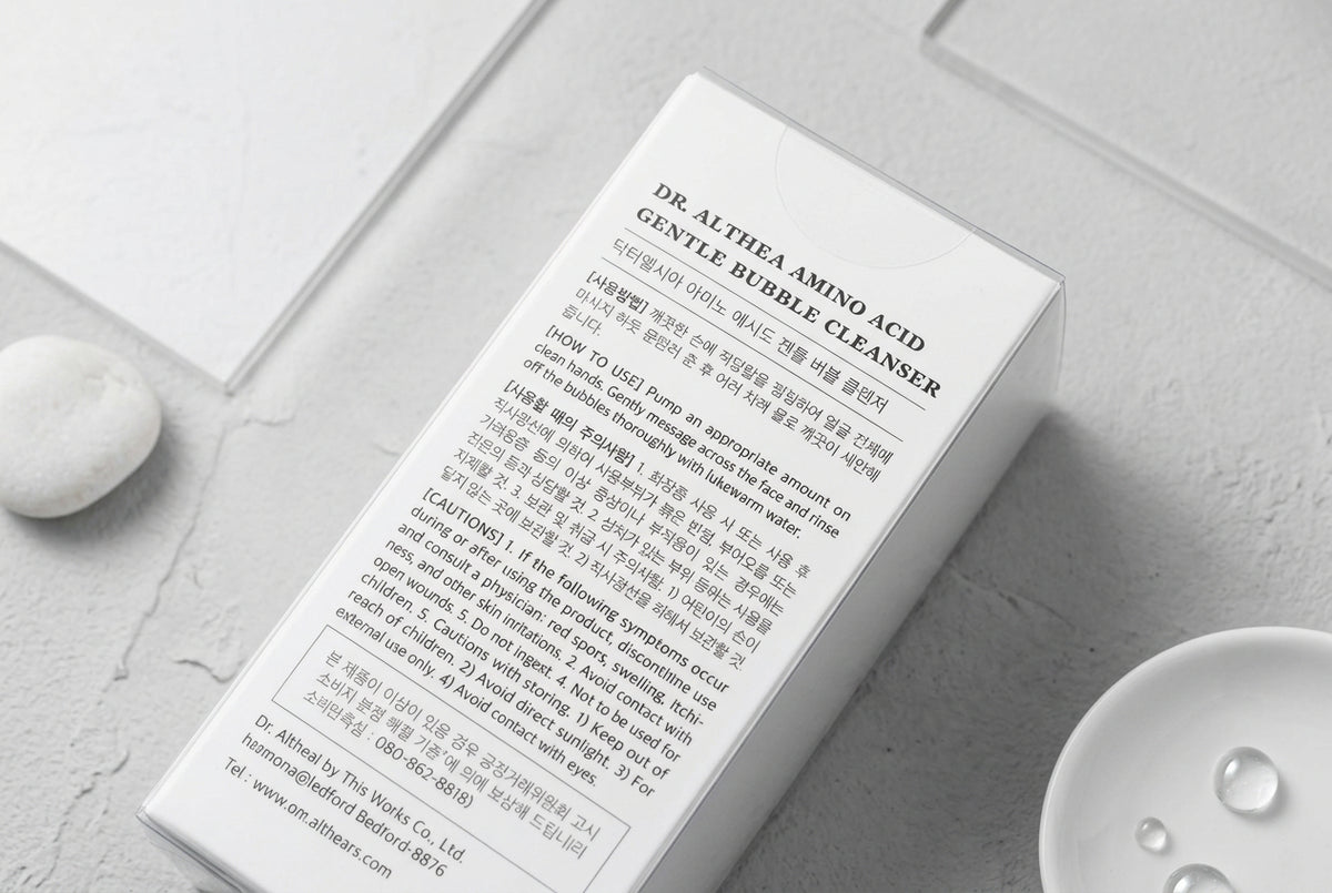A close-up of a white product box or insert card showing the text 'DR. ALTHEA AMINO ACID GENTLE HEBBLE CLEANSER' in black font, photographed on a dark wooden surface.